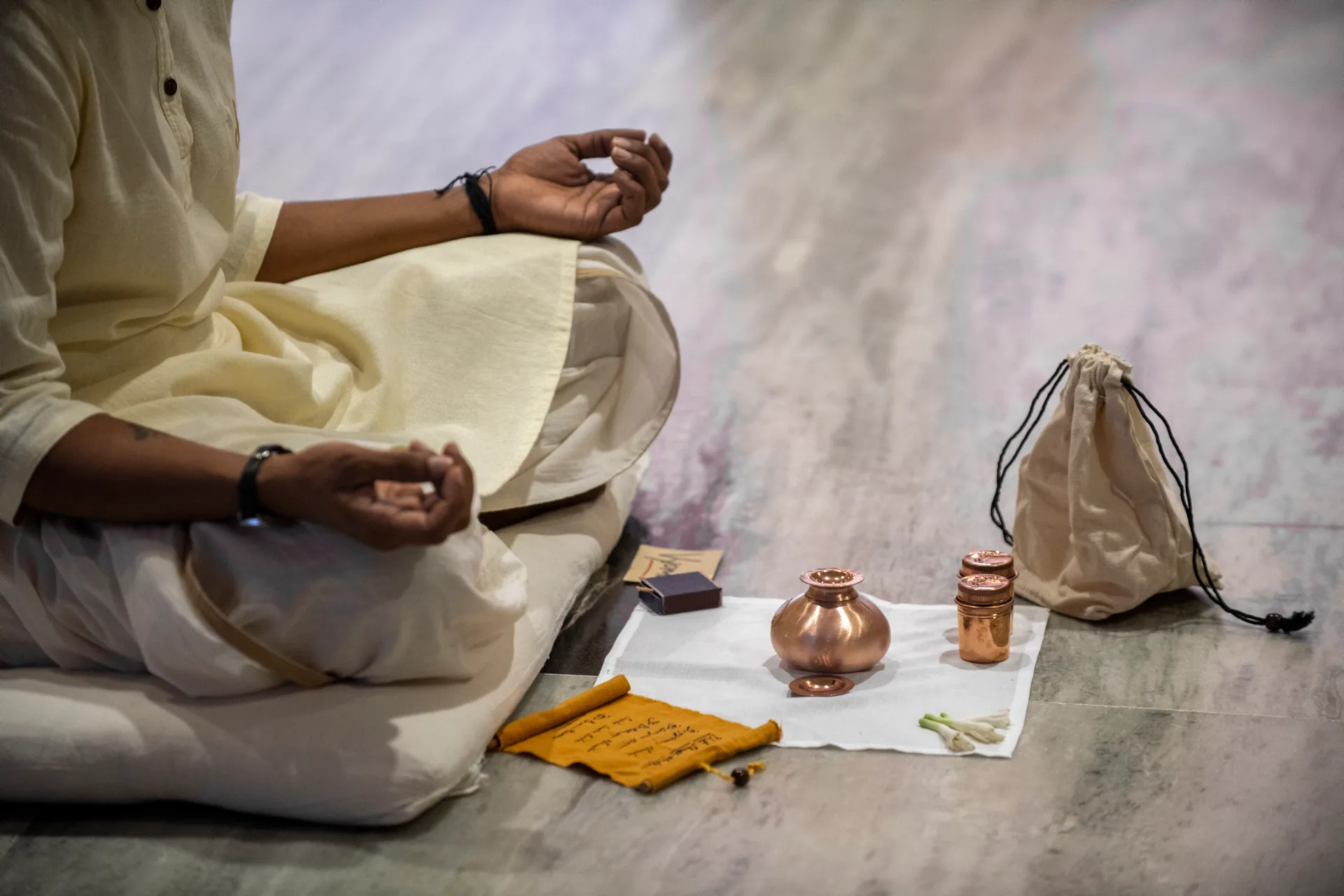 A quiet ritual arrangement — a copper vessel and a scroll before a seated practitioner.